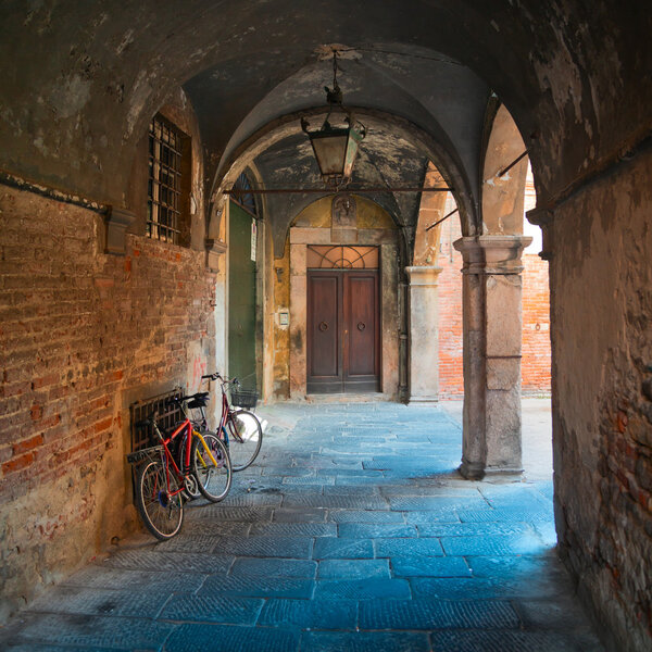 Ancient arcade and bikes in Lucca, Tuscany, square composition