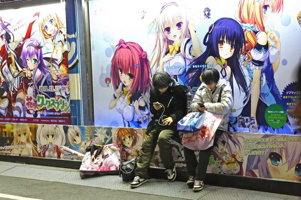 Adolescentes que ficam sob cartazes de anime — Fotografia de Stock