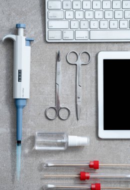 Fotokopi alanı olan boş ekranlı tablet, cerrahi makas, antibakteriyel sprey, labaratuvarda gri arka planda çubuk ve pipet. Virüslere karşı önlem ve koruma. Coronavirus, COVID-19 konsepti