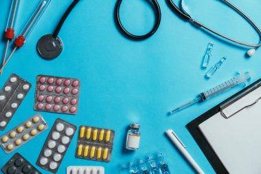 Steteskop, bez, hap, şırınga, aşı, ampul ve pano. Kopya alanı, başlık modeli, mavi arkaplan içeren tıbbi afiş şablonu