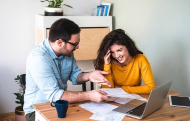 Mutlu karı koca internette iyi haberler okuyor. Heyecanlı çift dizüstü bilgisayarda iyi haberler okuyor, elinde bankadan olumlu kararlar alan gülümseyen adam, ipotek veya kredi onaylı e-posta alıyor