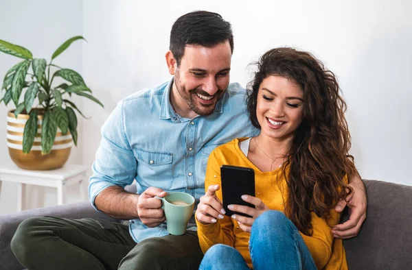 Mutlu görünen bir çift cep telefonu. Gülümseyen kız arkadaş oturma odasında erkek arkadaşına akıllı telefon gösteriyor. Yakışıklı adam elinde kahve fincanı tutuyor ve bir kadını kucaklıyor. Boş zamanlarını evde birlikte geçiriyorlar.