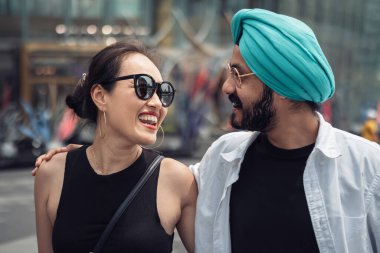 Açık havada kucaklaşan melez mutlu çifti yakından çek. Gülümseyen bir çift dışarıda sarılıp yürüyorlar. Kopya alanı ile tüketim kavramı