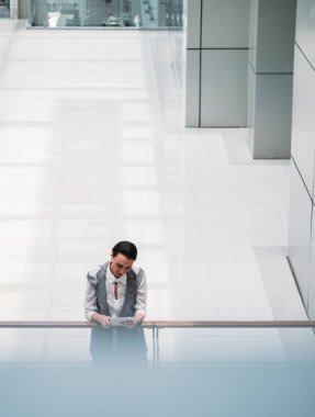 Modern koridorda dijital tablet kullanan bir iş kadını. Ciddi bir iş kadını boş koridorda duruyor ve beyaz tablete bakıyor.