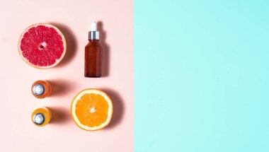 Çok renkli arka planda üç şişe hyaluronik asit, kolajen ve C vitamini serumu. Yaşlanma önleyici cilt bakımı serumları ve pastel üzerinde meyveler. İki renkli arka plan ve kopyalama alanı.