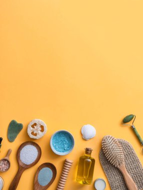 Sarı arka planda kaplıca tedavisi için sıfır atık kozmetik ürün. Cilt bakımı ve fotokopi alanı olan vücut bakımı için çevre dostu banyo ürünleri. Yeşim silindir, gua sha, saç fırçası, zeytin yağı, dudak kremi, yüz maskesi ve banyo tuzu.