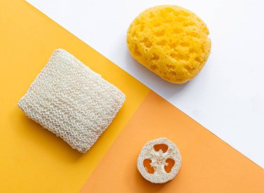 Banyo süngeri geometrik arka planda. Hijyen için sıfır atık banyo aksesuarı. Çok renkli, canlı bir arka plan. Çevre dostu sürdürülebilir yaşam tarzı kavramı 