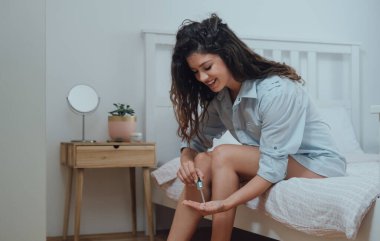 Elindeki sağlıklı cilt için nemlendirici serum kullanan bir kadın. Güzel bir kadın evinde yaşlanma önleyici serum kullanıyor.