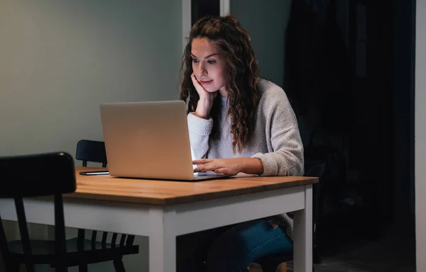 Woman working on laptop late at home.Concentrated businesswoman working late hours with her laptop. Working at home concept