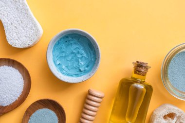 Doğal kozmetik ürünleri, sarı arka planda kaplıca güzelliği için fotokopi alanı ile birlikte. Banyo tuzu, kil, lif, zeytin yağı, masaj silindiri, sünger taşı ve yüz maskesi. Çevre dostu, sıfır atık banyo güzellik ürünleri
