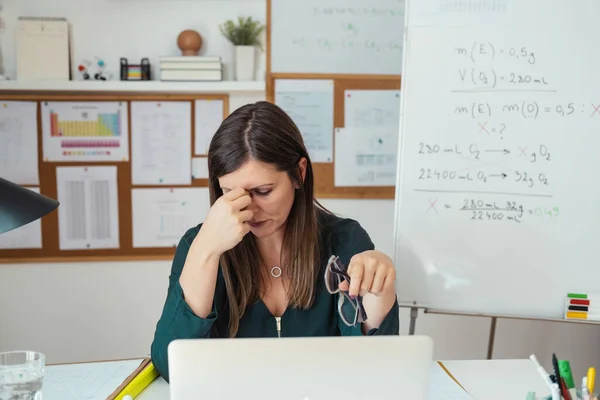 Young tired female professor having headache. Teacher holding online class for e-learning students at home during COVID-19 pandemic period. Stressed woman take off glasses feel pain rub closed eyes tired of computer screen, working at home, distance