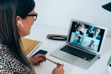 İş kadınlarının pandemik dönemde iş arkadaşlarıyla yaptığı görüntülü telefon görüşmelerini kapatın. Gülümseyen iş kadını internet konferansında müşterilerle ya da iş arkadaşlarıyla evde çalışan dizüstü bilgisayar ve bluetooth kulaklık kullanarak tartışıyor.