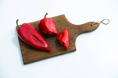 Tahta kesme tahtasındaki kırmızı biberler beyaz arkaplanda izole edilmiş.