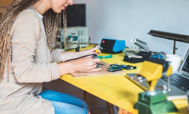 Devre kartında lehim yapan tanınmayan bir kadın. Devre kartındaki elektronik cihazı tamir eden kız. Bir bilgisayarın ana panosunu tamir eden bir bilişim işçisi. Profesyonel teknik servis. Teknoloji.