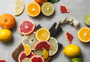 Kesme tahtasında taze meyve dilimleri. Mutfak masasında ahşap kesim tahtasının üzerinde renkli turunçgil dilimleri. Sıfır atık, plastiksiz ve fotokopi alanı ile çevre dostu yaşam tarzı kavramı