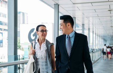 İş adamı ve iş kadını yürüyor ve konuşuyor. Gülümseyen iş adamları birlikte yürüyorlar