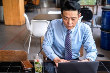 Kafeden dizüstü bilgisayarla çalışan ciddi bir iş adamı