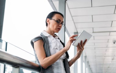 Tablet kullanan ciddi iş kadınlarının portresi. Modern balkonda dijital tablet kullanan güzel bir iş kadını.