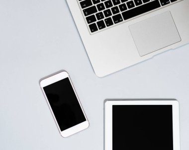 Dizüstü bilgisayarın üst görüntüsü, dijital tablet ve cep telefonu gri arka planda izole edilmiş. Kopyalama alanı olan düz