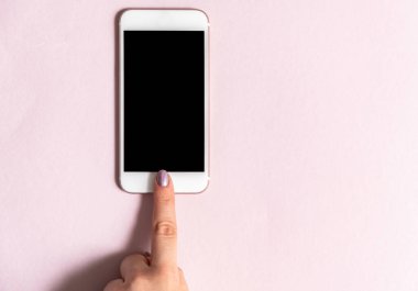 Pembe arka planda beyaz cep telefonunu tutan ellerin görüntüsü. Pembe arka planda beyaz cep telefonunu tutan ellerin görüntüsü. Düz yatıyordu. Üst görünüm