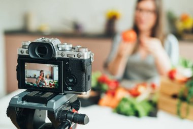 Güzel bir kadın ev mutfağında çevrimiçi yemek kursunun video dersini kaydediyor. Kameraya odaklan. Kadın aşçı youtube yemek kanalı için sağlıklı yemek hazırlama videosunu çekiyor.