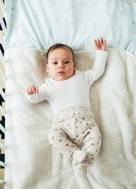 Sevimli Bebek 'in En İyi Görünüşü Kameraya Bakıyor ve Sabahleyin beşiğinde dinlenen küçük bir çocuğun portresinde yatıyor.