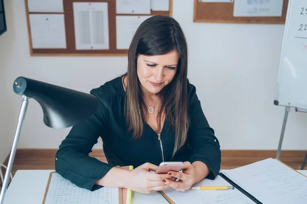 Female professor having break with online class and using her mobile phone to send text message.Teacher is working from home with E-learning students teaching online lessons during isolation period.