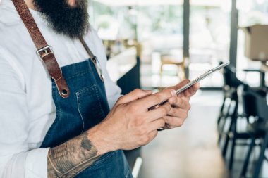 Bir kafede dijital tablet kullanan tanınmayan bir barista. Dövmeli, dijital tabletli, internetten kitap okuyan ya da restoranda çalışırken bir şeyler izleyen erkeklerin fotoğraflarını çek..