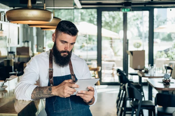 Jóképű Barista Digitális Tablet Használata Egy Kávézóban Komoly Pincér Szakállal — Stock Fotó