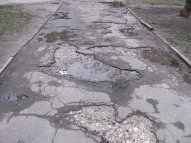 Kırık asfalt yolda, çukurda çakıl var.