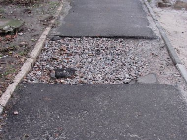 Kırık asfalt yolda, çukurda çakıl var.