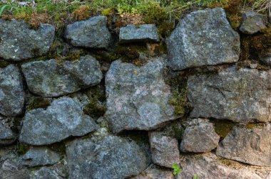 Kırıklarda yosun olan sert granit taşlardan bir duvar.