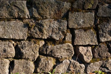 Kırıklarda yosun olan sert granit taşlardan bir duvar.
