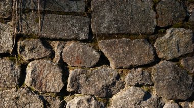 Kırıklarda yosun olan sert granit taşlardan bir duvar.