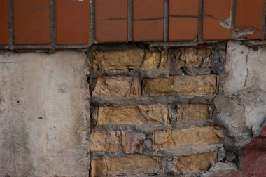Beton, tuğla ve kahverengi kiremitli pürüzlü bir duvar.