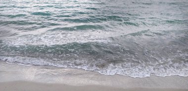 Deniz dalgaları kıyıya vuruyor, geniş bir zemin.