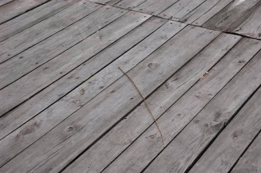 Paslı çiviler ve görülebilir boşluklarla gri çatlamış tahtalardan yapılmış eski ahşap yürüyüş yolu terk edilmiş bir atmosfer yaratıyor..