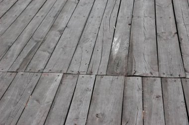 Paslı çiviler ve görülebilir boşluklarla gri çatlamış tahtalardan yapılmış eski ahşap yürüyüş yolu terk edilmiş bir atmosfer yaratıyor..