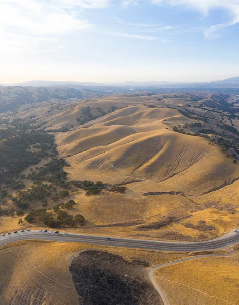Golden sunlight shines on the rolling hills in Northern California. These beautiful, eroded hills turn green once winter brings seasonal rain to the region.