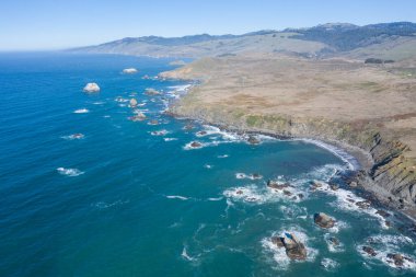 Pasifik Okyanusu, güzel bir kış gününde Kuzey Kaliforniya 'nın engebeli kıyı şeridine karşı kıyıya vurur. Manzaralı Pasifik Sahil Otoyolu Kaliforniya 'nın büyük bir kısmı boyunca uzanıyor..