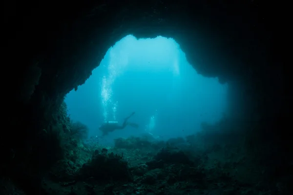 Ныряльщики с аквалангом у рта глубокой пещеры — стоковое фото