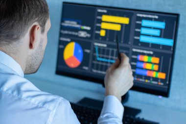 Takım elbiseli bir adam ofisteki bir bilgisayarda çalışıyor..