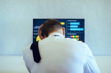 Takım elbiseli bir adam ofisteki bir bilgisayarda çalışıyor..