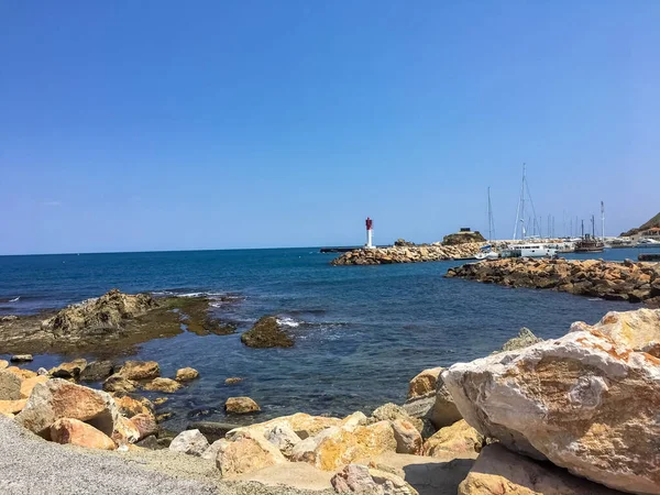 Ön planda küçük deniz koyları ve sarı volkanik kayalar var.