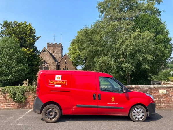 Trysull, İngiltere, İngiltere. Yolda kırmızı bir Kraliyet Posta arabası ve arka planda da eski bir kilise.