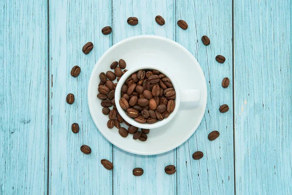 Kahve çekirdekleri ile dolu beyaz bir fincanın üst görüntüsü. Espresso çekirdekleri daire içine alındı. Mavi arkaplan.                             