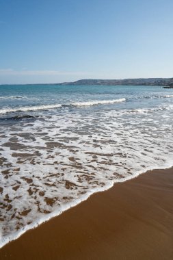 Calabria, İtalya 'daki Crotone' daki İyon Denizi 'ne bakın. Arka planda, dağlardan ve tepelerden oluşan bir manzara, doğal bir Akdeniz atmosferi sağlar. Poster, seyahat, turizm ve doğa için ideal.