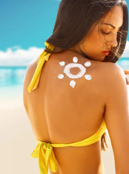 Mulher com protetor solar em sua pele na praia em maiô — Fotografia de Stock
