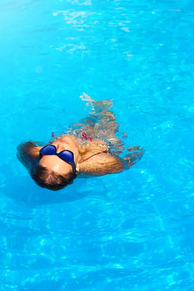 Mujer joven flotando en una piscina, mirando al cielo . — Foto de Stock