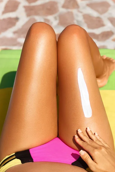 Mujer aplicando protector solar a sus piernas — Foto de Stock